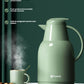 The sage green FEENIK thermal jug with steam rising from a mug, highlighting key features: 48-hour long-lasting heat preservation, food-grade materials, and being safe for pregnant women and babies.