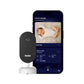 Owlet Dream Sight baby monitor camera next to smartphone app showing live feed of sleeping baby, room temperature (68°F), humidity (32%), low noise level, and video clips
