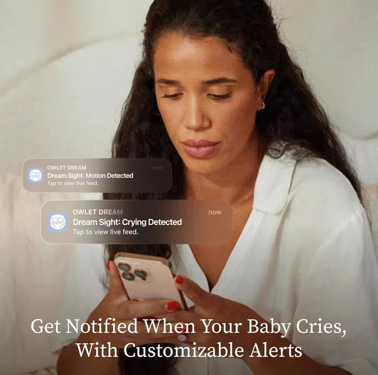 Woman receiving real-time smartphone notifications from Owlet Dream Sight baby monitor: “Dream Sight: Crying Detected” and “Dream Sight: Motion Detected”