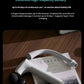 The Philips massage gun resting on a magazine, showcasing its sleek design and Type-C charging port. Features a 2500mAh battery that lasts up to 240 minutes per charge—ideal for daily use over 24 days.