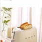 The Smeg 50's Style toaster with two slices of perfectly browned toast popping up, set on a breakfast table to illustrate its 6 versatile baking settings and 4 functions for customized toasting.